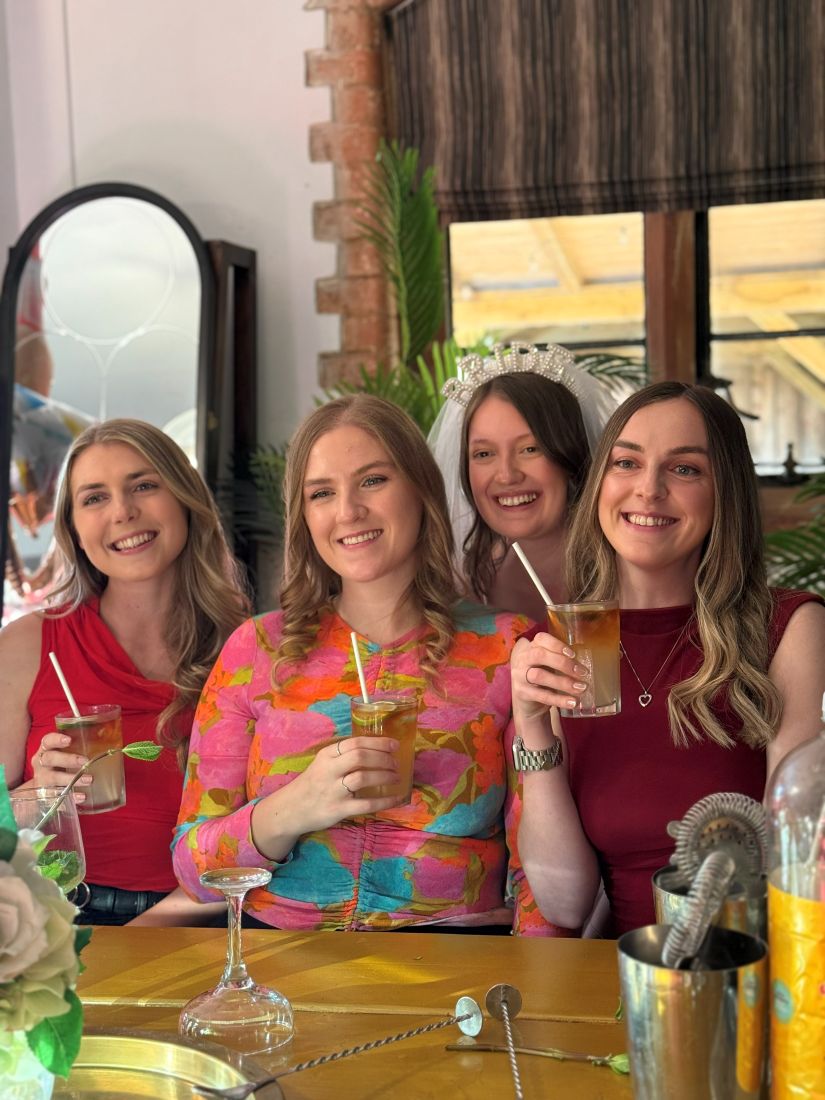 Four friends holding up the cocktails they just made